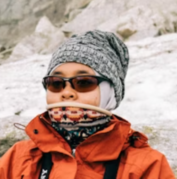 Man in winter hiking gear and sunglasses on snowy terrain