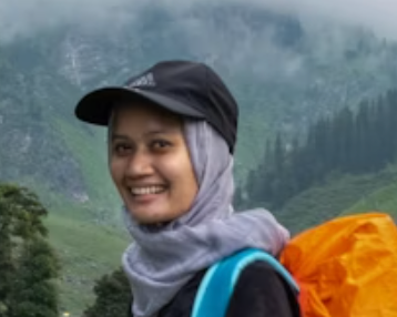 Smiling woman with headscarf and backpack in the mountains